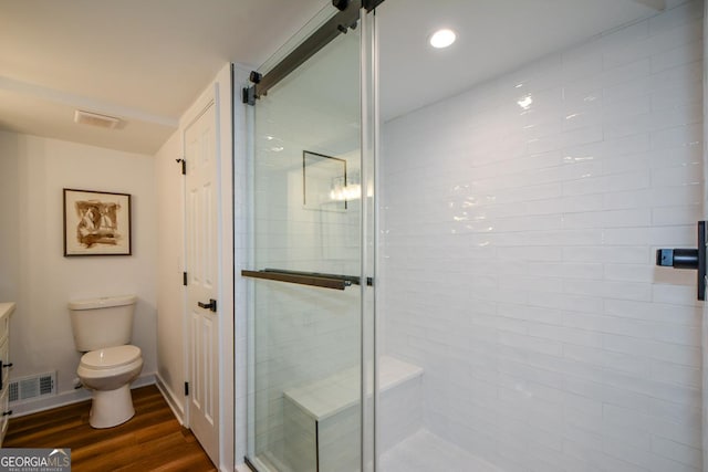 full bath with toilet, a stall shower, visible vents, and wood finished floors