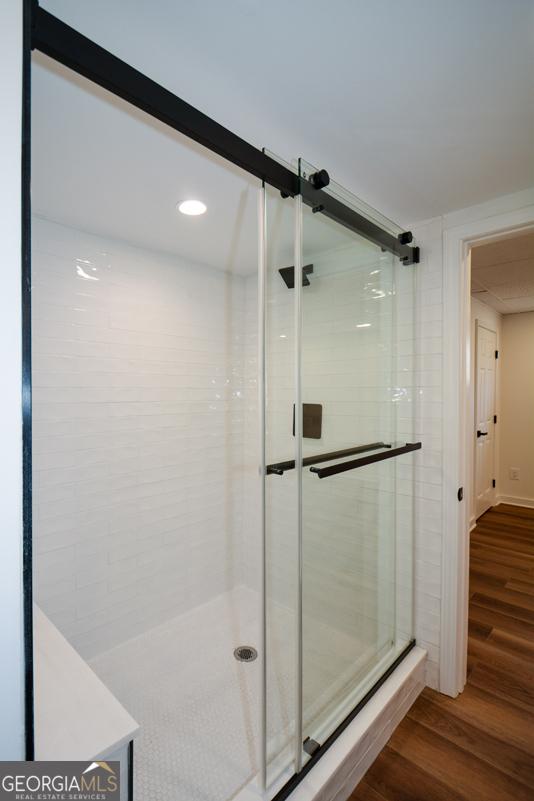 bathroom with wood finished floors and a shower stall