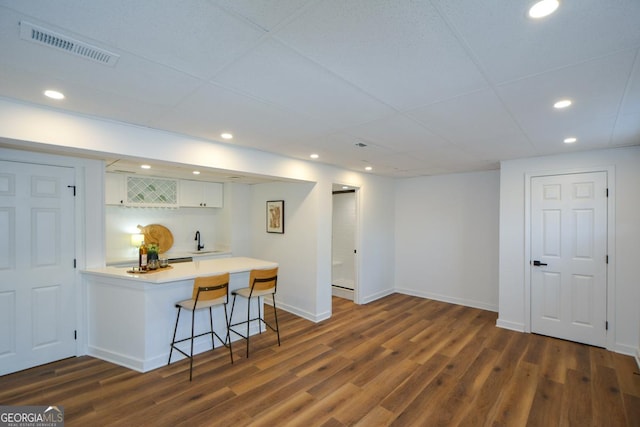 kitchen with visible vents, a breakfast bar area, a peninsula, light countertops, and white cabinetry