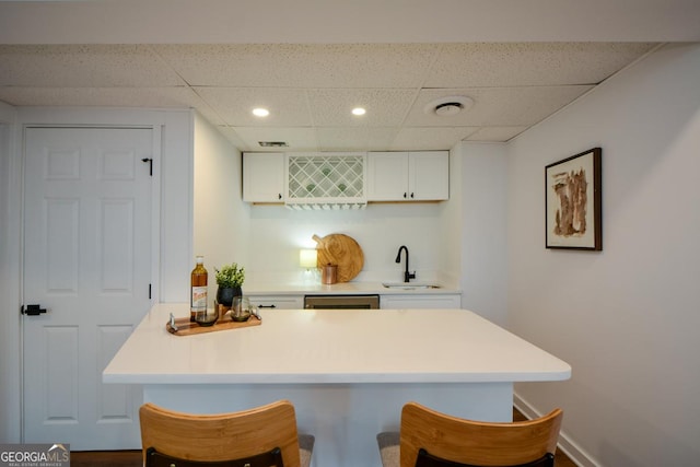 kitchen with light countertops, a sink, a kitchen breakfast bar, and white cabinetry