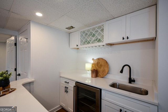 bar featuring wine cooler, a sink, a paneled ceiling, and wet bar