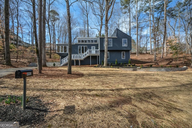 view of front of home with a sunroom, stairway, and a front lawn