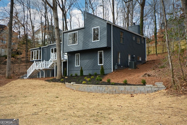 back of house with central AC, a chimney, and a sunroom