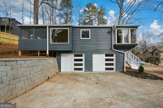 view of front of property featuring a sunroom, driveway, stairway, and an attached garage