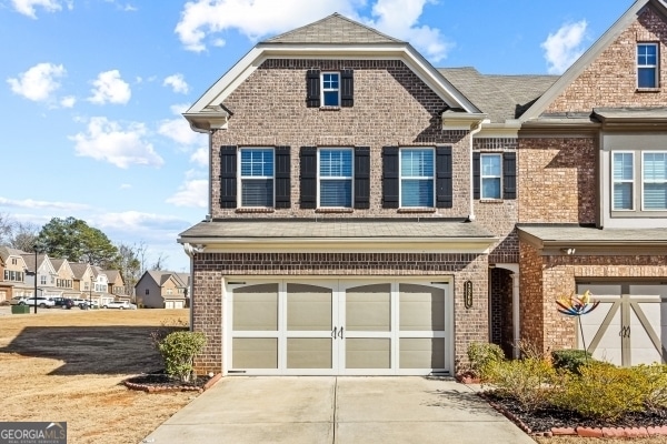 view of front facade with driveway, brick siding, and an attached garage