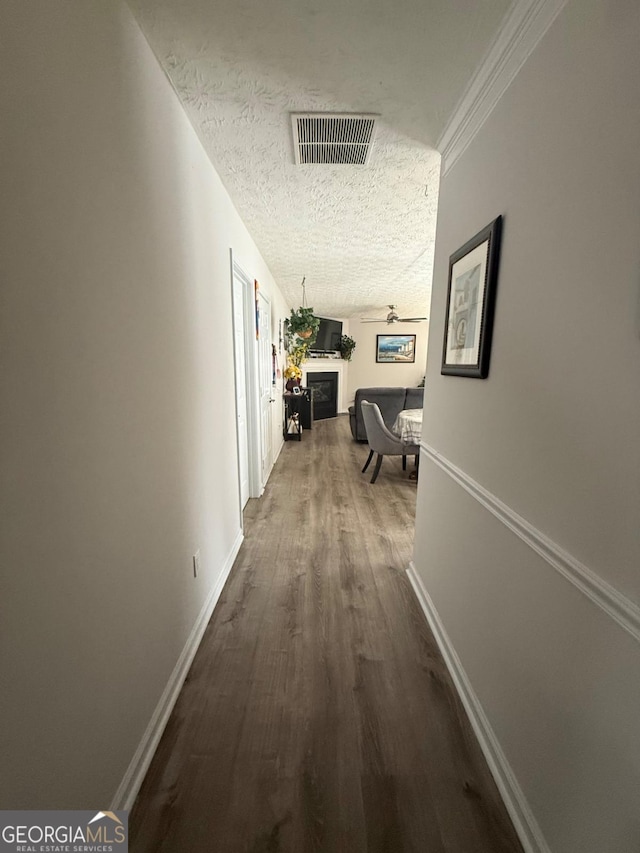 corridor with a textured ceiling and hardwood / wood-style flooring