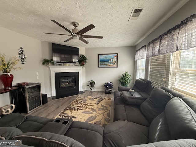 living room featuring a textured ceiling, ceiling fan, and wood-type flooring