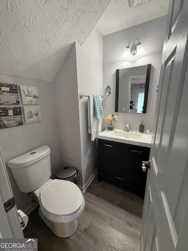 bathroom featuring a textured ceiling, toilet, vanity, and wood-type flooring