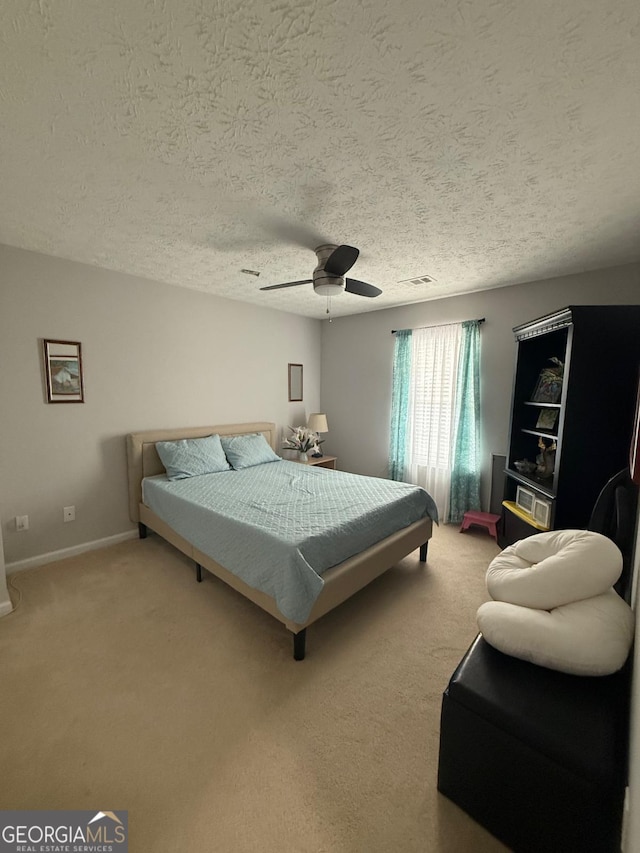 carpeted bedroom featuring ceiling fan and a textured ceiling