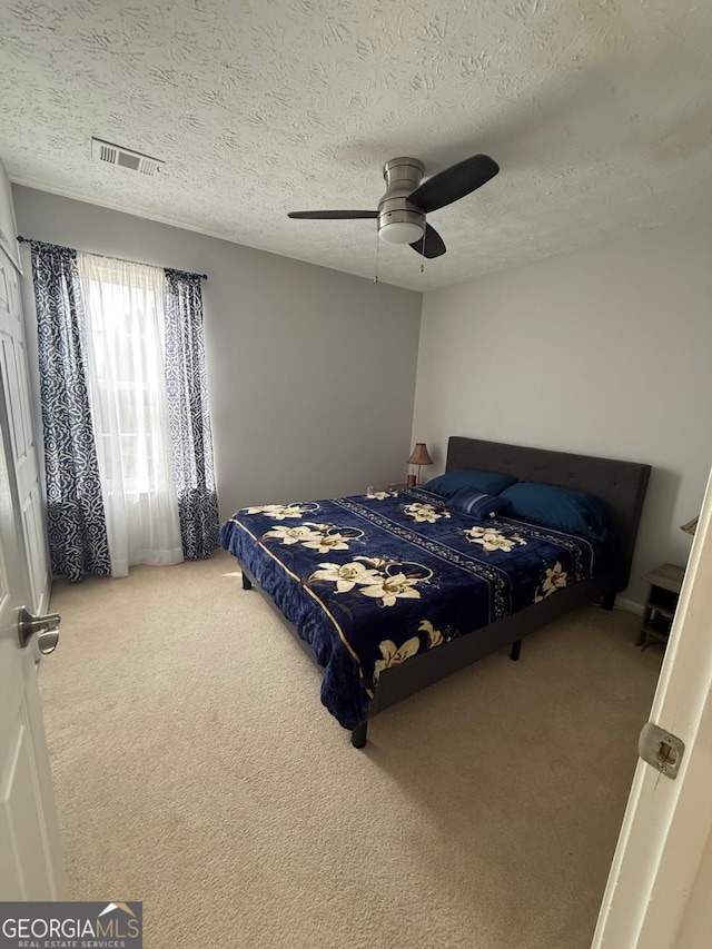 carpeted bedroom with a textured ceiling and ceiling fan