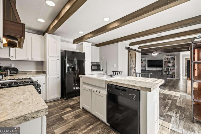 kitchen featuring an island with sink, a barn door, black appliances, white cabinets, and dark hardwood / wood-style floors