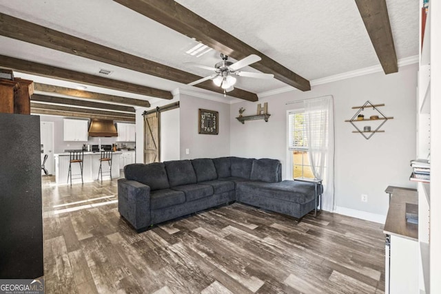 living room with dark hardwood / wood-style flooring, a barn door, beam ceiling, and ceiling fan