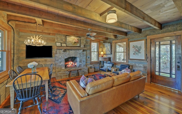 living room with beam ceiling, wood-type flooring, a chandelier, wood ceiling, and a fireplace