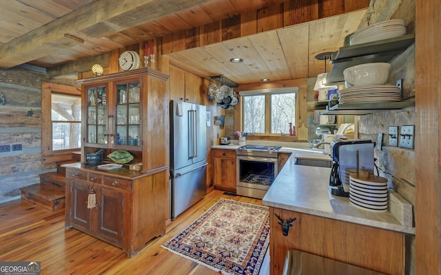 kitchen with wooden walls, stainless steel appliances, wood ceiling, sink, and light wood-type flooring