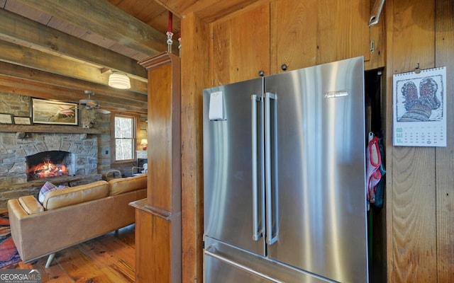 kitchen featuring beam ceiling, wooden walls, dark hardwood / wood-style flooring, a fireplace, and high end refrigerator