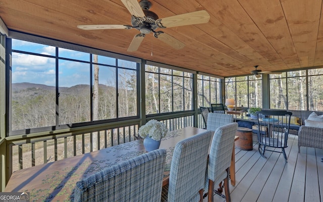 sunroom featuring a mountain view, wooden ceiling, and ceiling fan