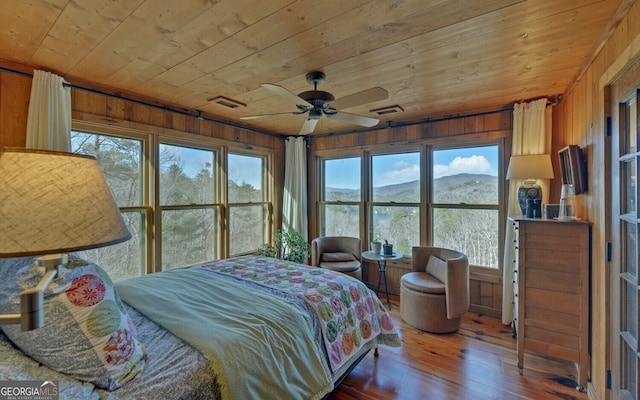 bedroom featuring hardwood / wood-style flooring, a mountain view, wood ceiling, and wood walls