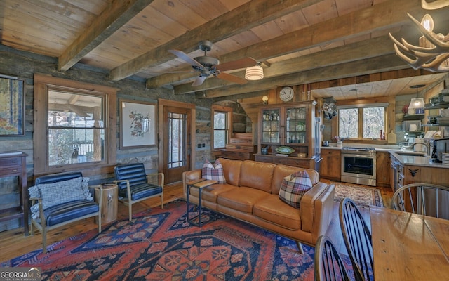 living room featuring beamed ceiling, dark hardwood / wood-style flooring, wooden ceiling, and ceiling fan