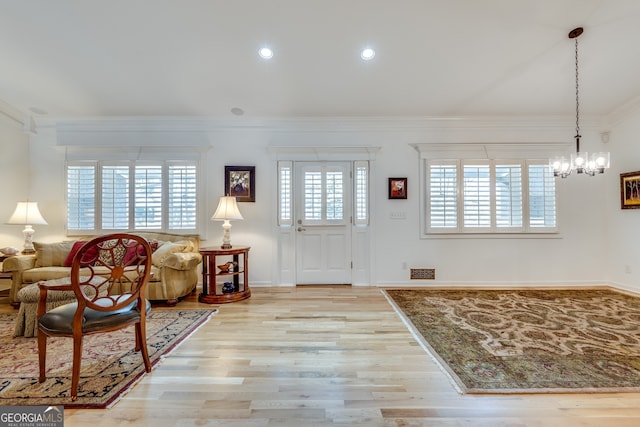 entrance foyer with a chandelier, ornamental molding, and light wood-type flooring