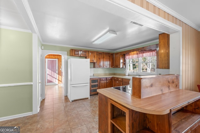 kitchen with arched walkways, light countertops, open shelves, and freestanding refrigerator