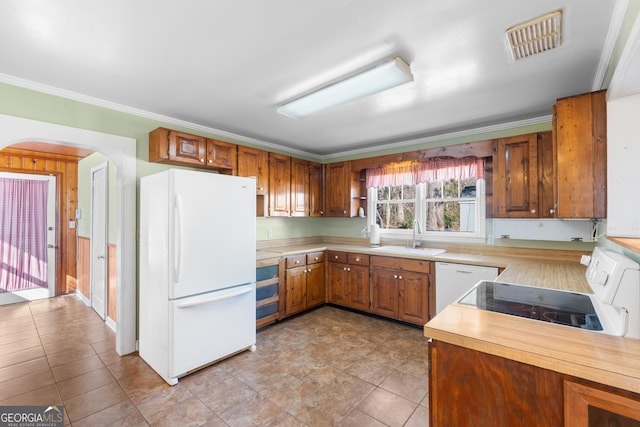 kitchen with arched walkways, light countertops, visible vents, a sink, and white appliances