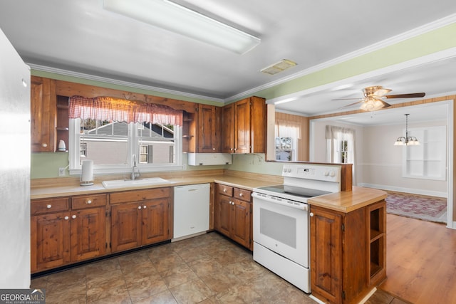 kitchen with pendant lighting, white appliances, brown cabinets, and a sink