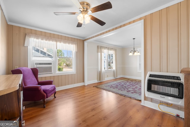 living area with ornamental molding, plenty of natural light, heating unit, and wood finished floors