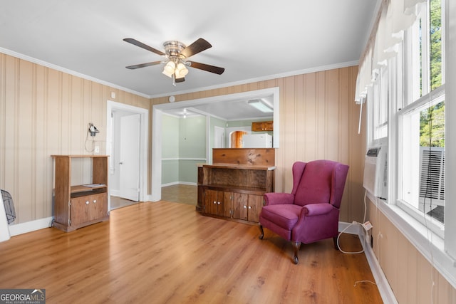 living area featuring baseboards, a ceiling fan, light wood-style flooring, and crown molding