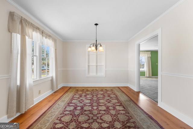 dining area featuring baseboards, ornamental molding, wood finished floors, and an inviting chandelier