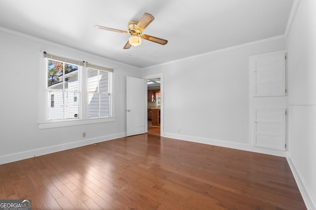 spare room with baseboards, ornamental molding, and wood finished floors