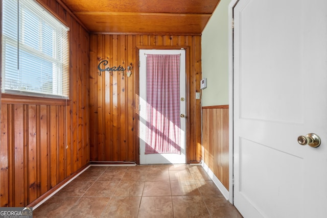 doorway to outside with wood walls, wooden ceiling, and tile patterned floors