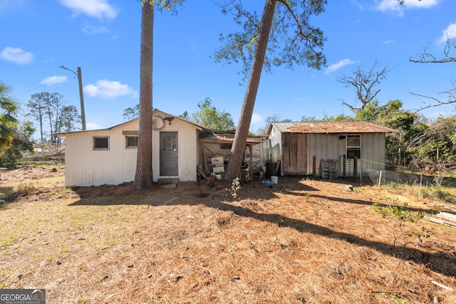 back of house featuring an outbuilding and fence