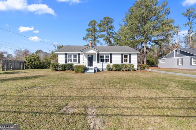 view of front facade with a front yard, fence, and a chimney