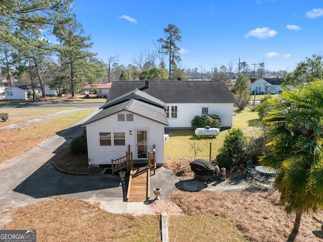 view of front facade featuring roof with shingles and driveway