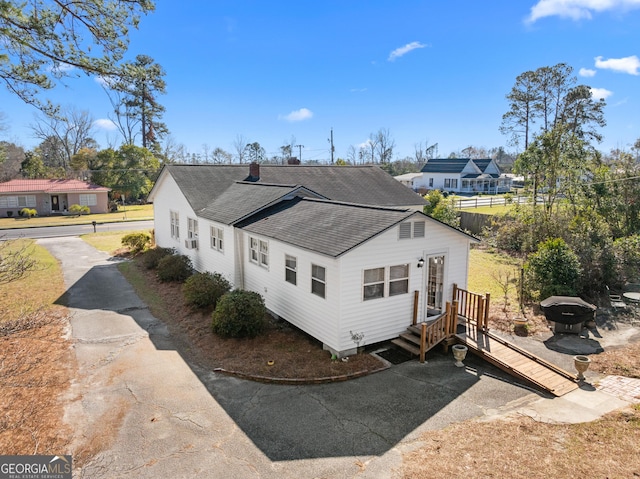 view of property exterior featuring a shingled roof and a residential view