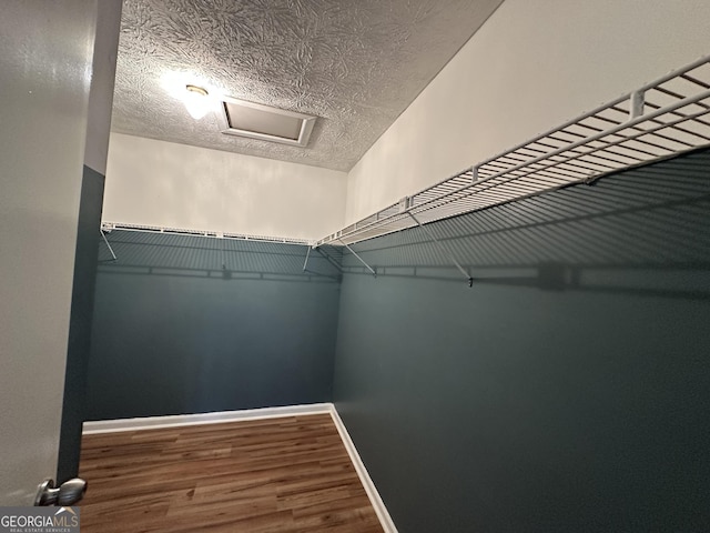 walk in closet featuring wood finished floors and attic access