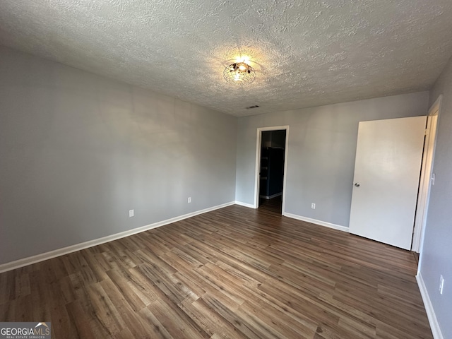 unfurnished bedroom featuring dark wood-style floors, baseboards, and a textured ceiling