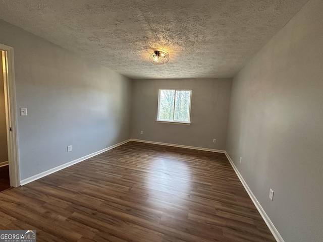 unfurnished room featuring dark wood-type flooring, a textured ceiling, and baseboards