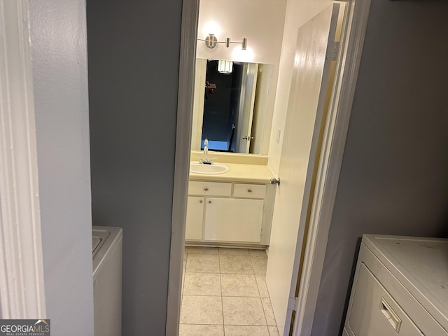 washroom featuring a sink, laundry area, light tile patterned flooring, and washing machine and dryer