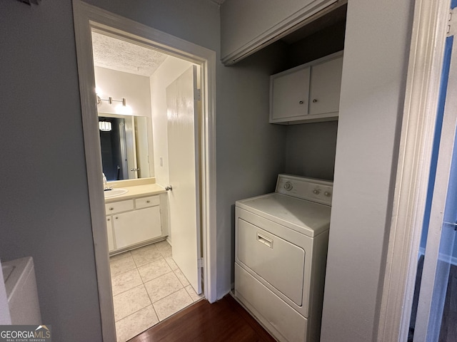 laundry room with cabinet space, washer / clothes dryer, tile patterned flooring, a textured ceiling, and a sink