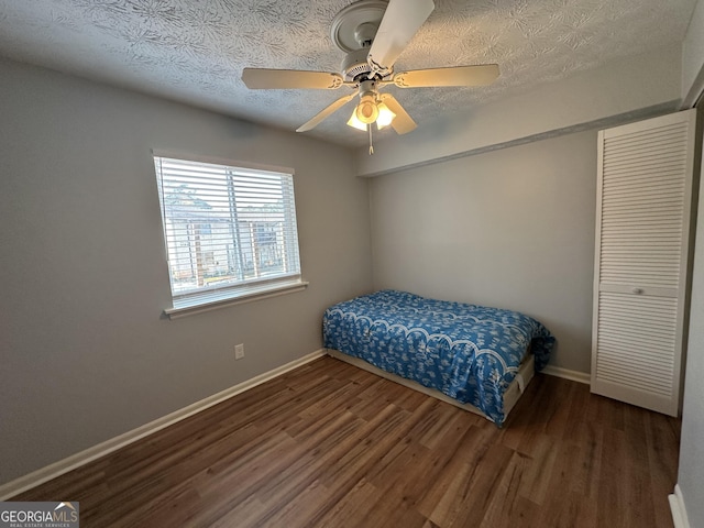 bedroom with ceiling fan, a textured ceiling, baseboards, and wood finished floors