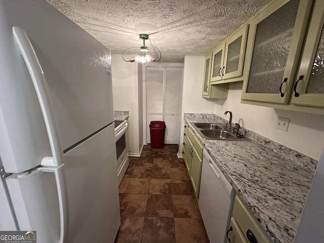 kitchen featuring a textured ceiling, white appliances, a sink, light countertops, and glass insert cabinets