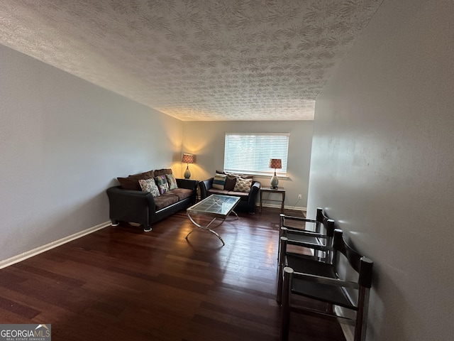 living room with a textured ceiling, baseboards, and wood finished floors