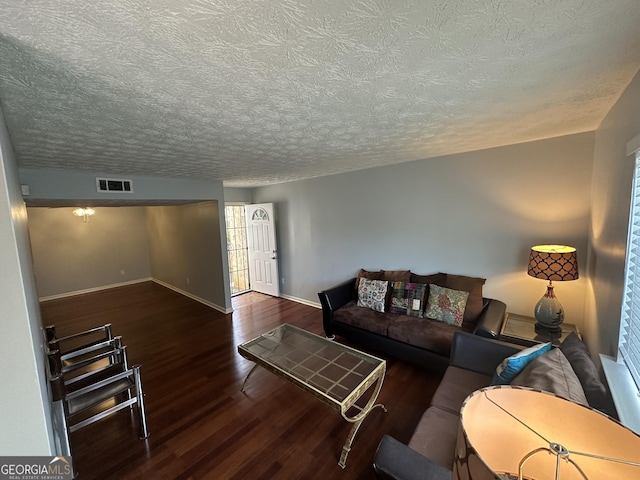 living area featuring a textured ceiling, wood finished floors, visible vents, and baseboards