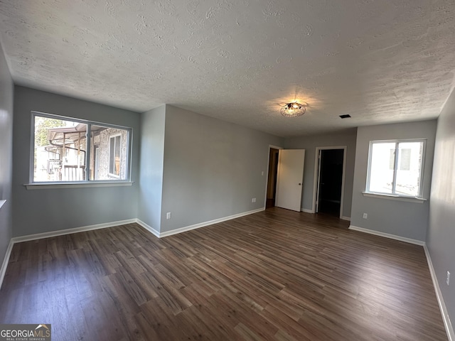 unfurnished room with baseboards, dark wood finished floors, and a textured ceiling