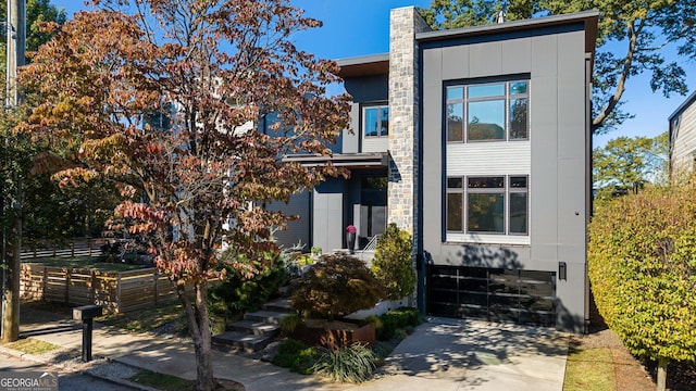 contemporary house featuring board and batten siding, concrete driveway, a garage, and fence