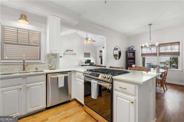 kitchen with appliances with stainless steel finishes, light hardwood / wood-style floors, white cabinetry, and kitchen peninsula