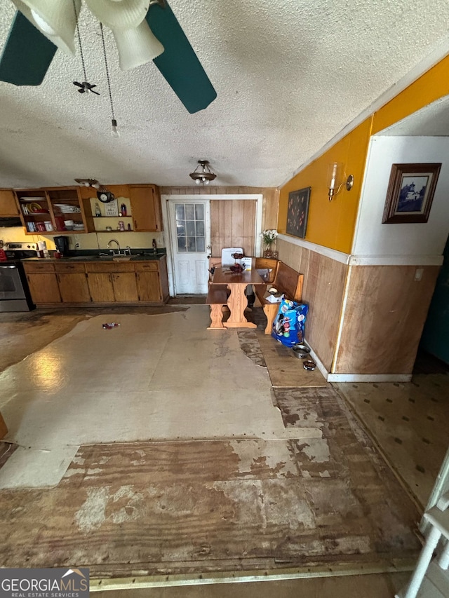 interior space featuring ceiling fan, sink, wood walls, and a textured ceiling