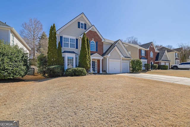 traditional-style home with a garage, a residential view, brick siding, and driveway