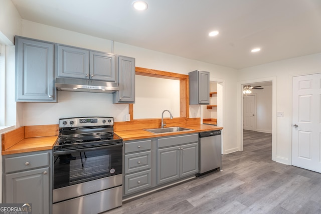 kitchen with hardwood / wood-style flooring, wooden counters, stainless steel appliances, ceiling fan, and sink